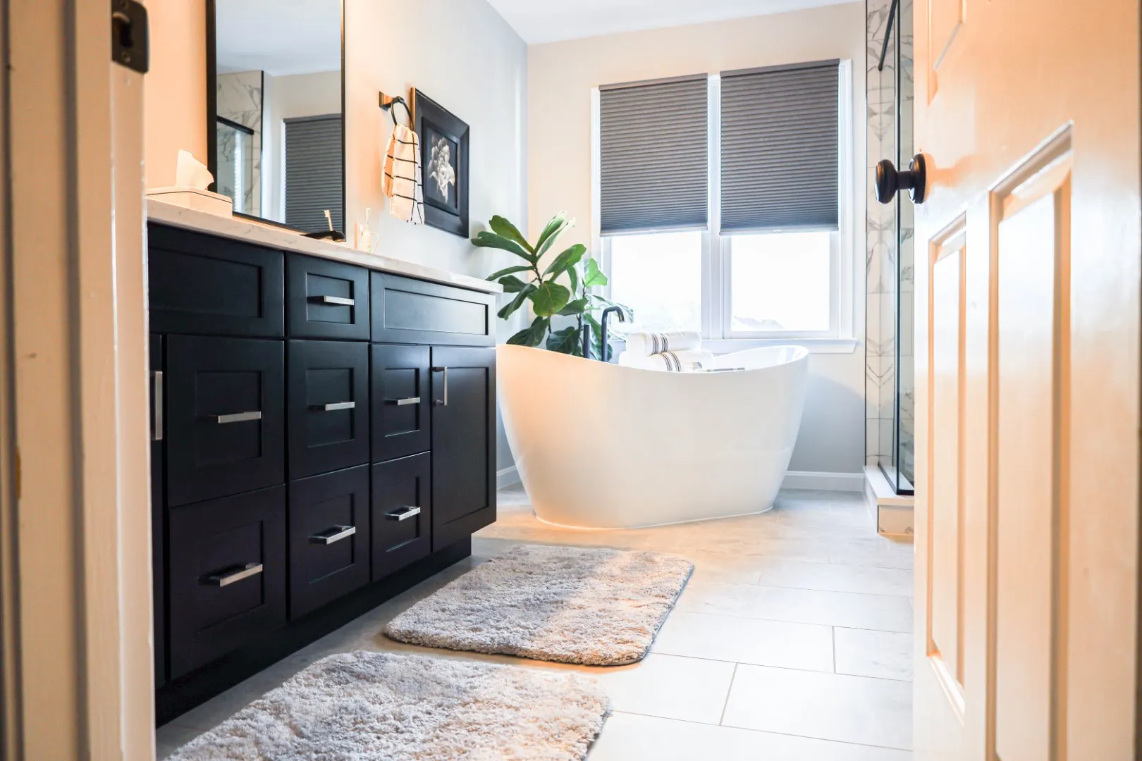 Beautiful master bathroom remodeling in Ellicott City MD featuring a freestanding tub, dark vanity, and glass shower.