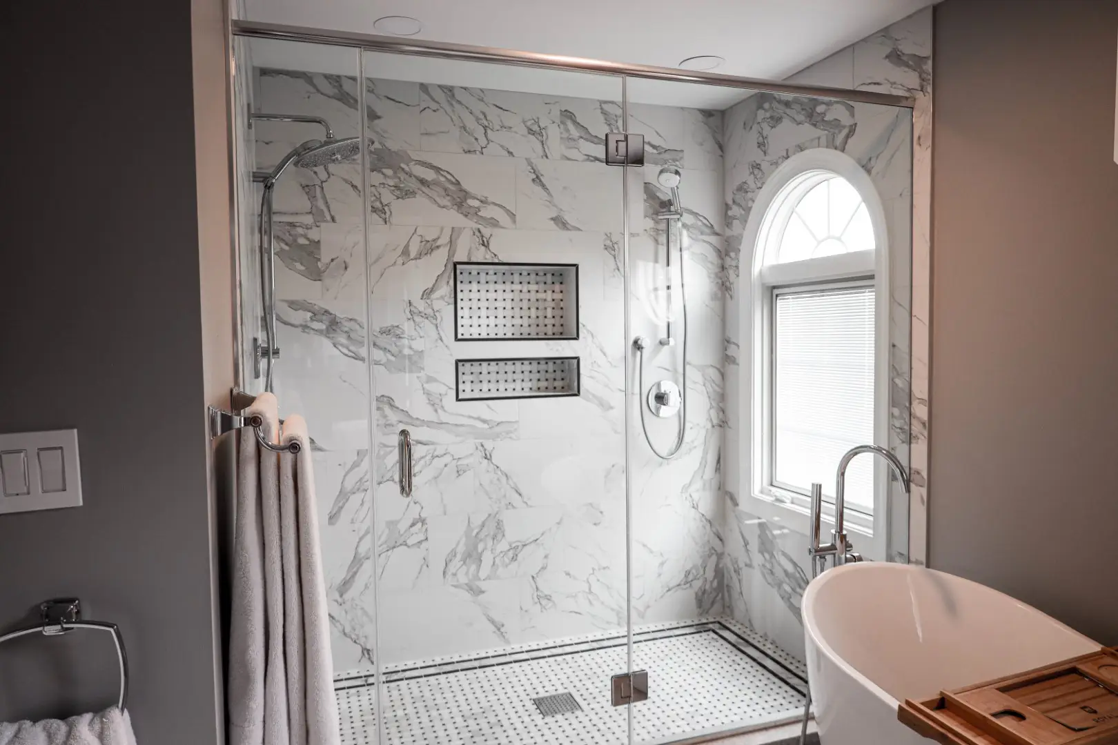 Stunning bathroom remodeling in Columbia MD featuring a large freestanding tub by a unique round window and a spacious vanity, designed by Anka Design Studio.