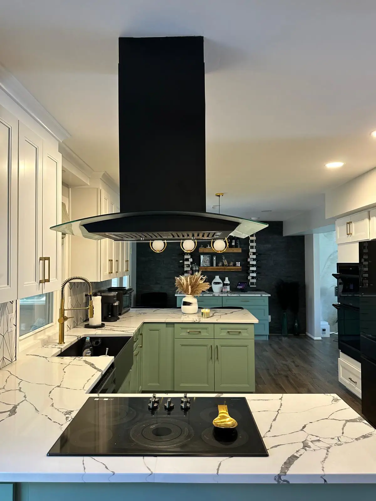 Complete kitchen remodeling in Owings Mills MD featuring sage green lower cabinets, white upper cabinets, and a striking black island range hood by Anka Design Studio.