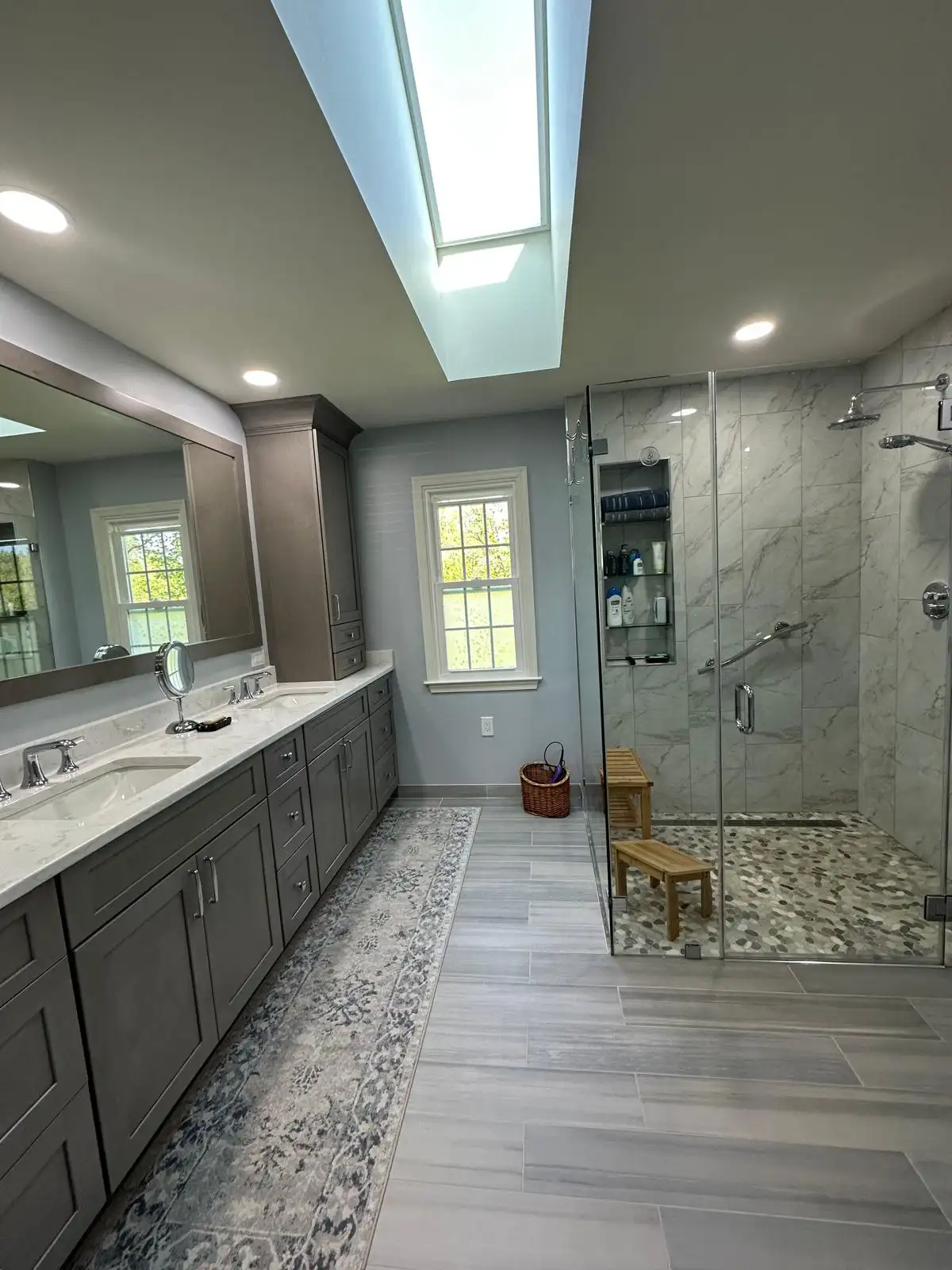 Close-up of a white undermount bathroom sink paired with a brushed gold widespread faucet on a marble-look quartz countertop over green cabinetry in Columbia, MD.