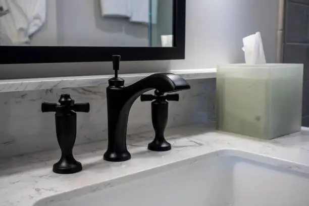 Close-up of a matte black faucet on a white marble vanity counter