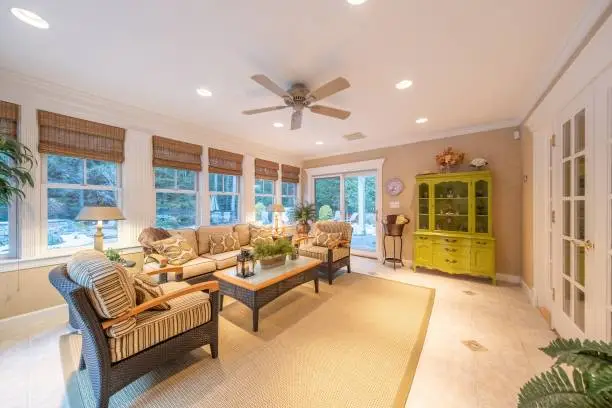 Four-season sunroom renovation with tile flooring and recessed lighting by Anka Design Studio