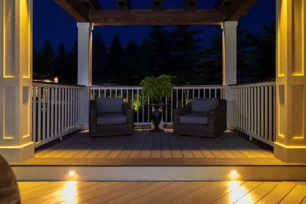 A deck with built-in bench seating, integrated planters, and post cap lighting at dusk