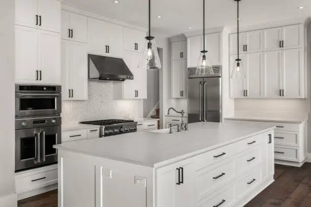 Beautifully finished kitchen renovation with custom white cabinetry, quartz countertops, large island and pendant lighting