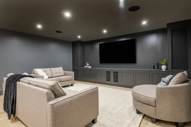 Finished basement converted into a modern home theater with tiered seating and projection screen